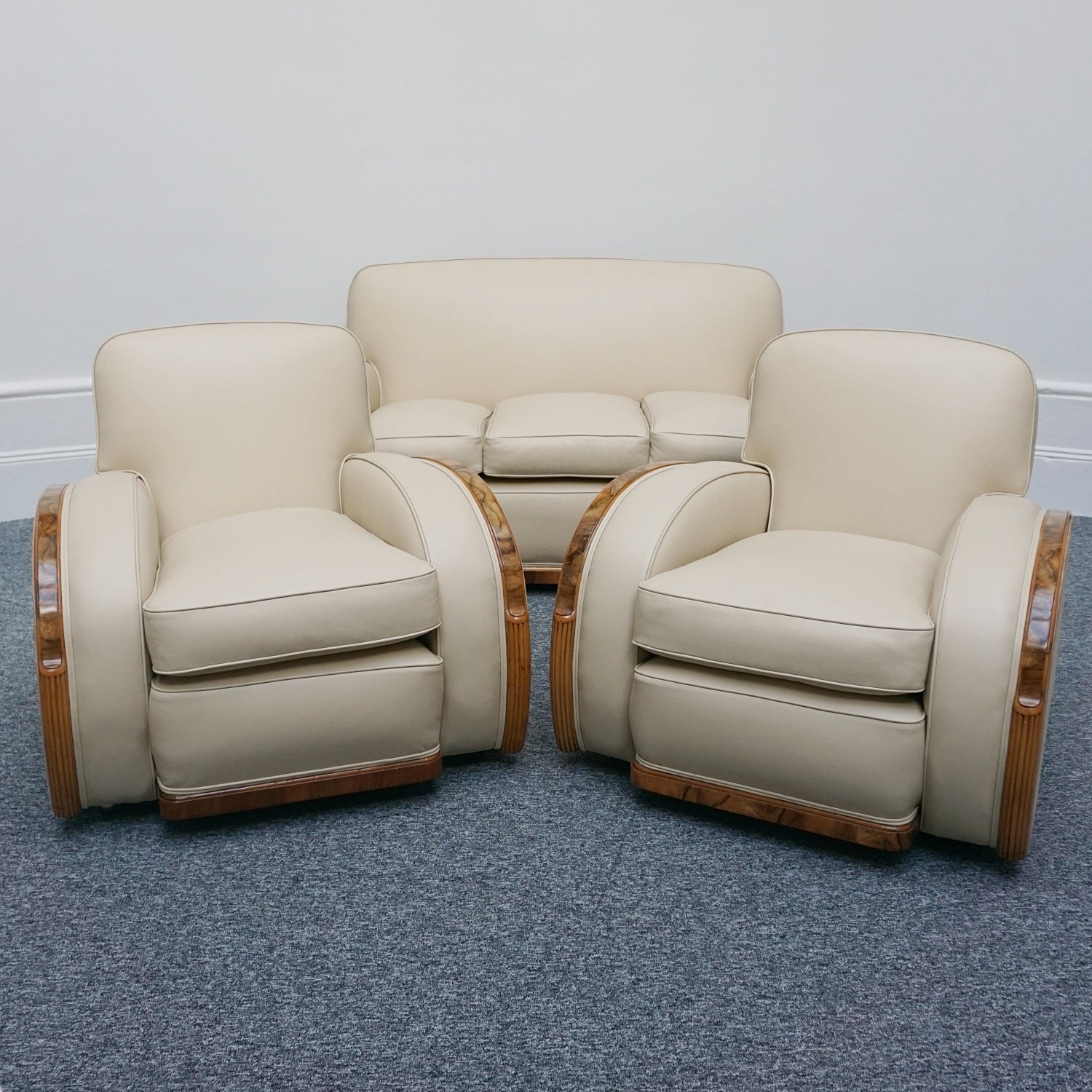 An Art Deco three piece tank suite by Heals of london. Made of Burr and solid walnut banding with reeded lower section, Upholstered in cream leather and contrasting faux suede