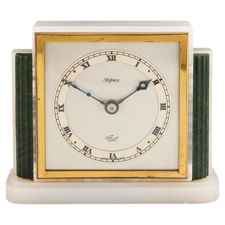 An Art Deco mantel clock by Asprey made of white marbled onyx and green bevelled malachite with a square clock face featuring roman numerals framed with brass